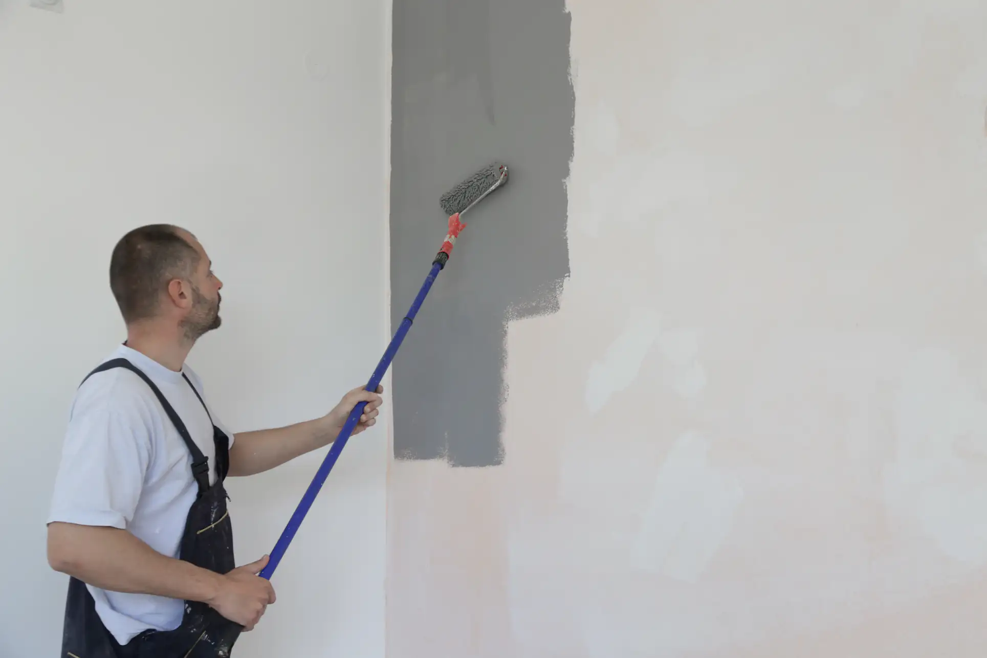 Professional painter applying a smooth gray finish to a wall in Essex County, Massachusetts, showcasing Fine Coat Painters' expertise in residential interior painting services