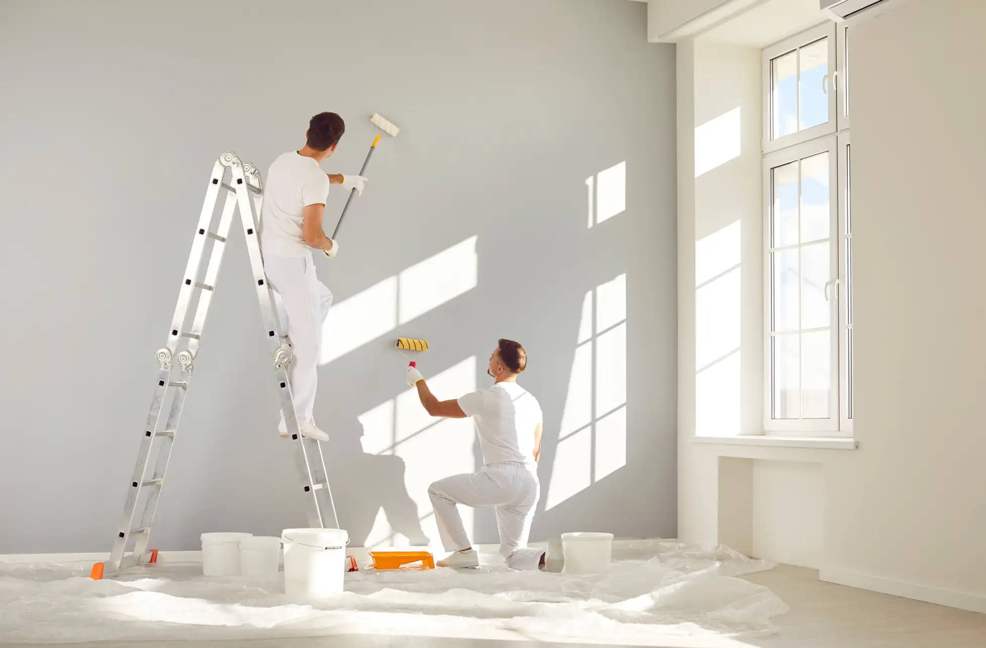 Skilled painters applying fresh coat of paint on interior wall in a home in Essex County, MA, showcasing Fine Coat Painters' precision and attention to detail in every project