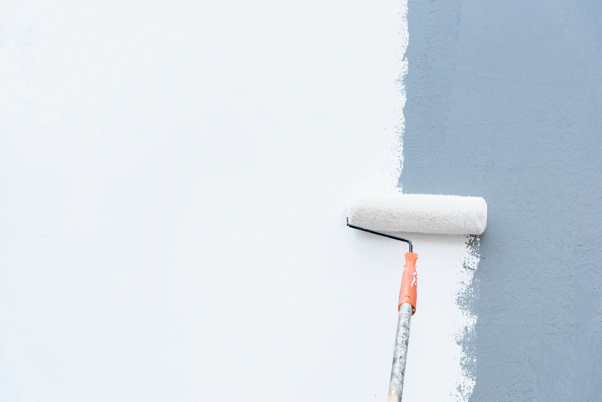 Skilled painter rolling white paint on a wall in Essex County, Massachusetts, ensuring a smooth, even finish for Fine Coat Painters' residential project