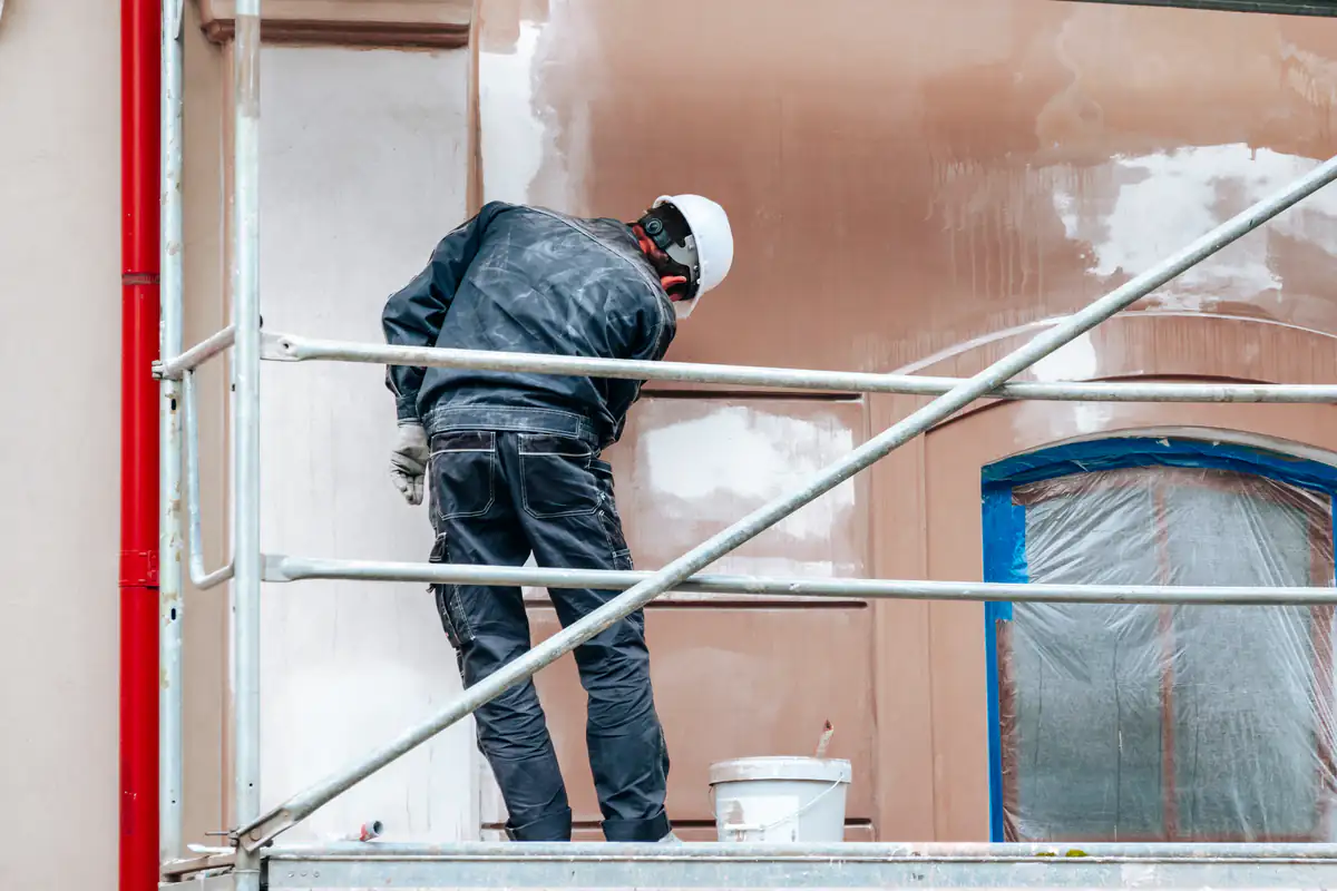 Fine Coat Painters' expert worker applying fresh paint to the exterior of a building in Essex County, MA, highlighting the precision and professionalism of the painting service